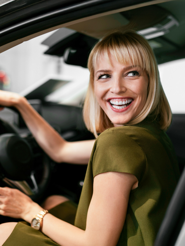 Frau sitzt im Auto und hält das Lenkrad